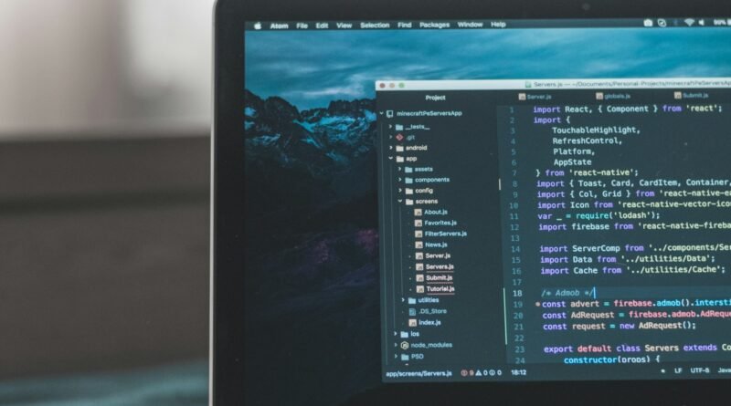 Laptop on a dark desk showing lines of source code in a code editor