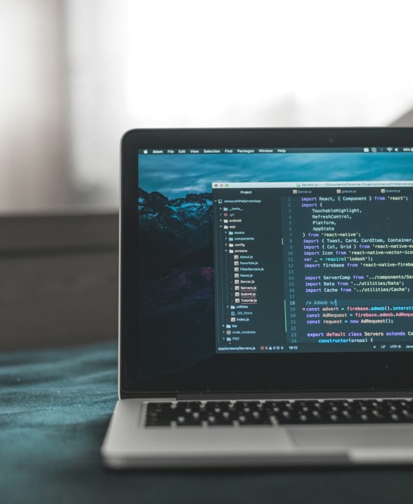 Laptop on a dark desk showing lines of source code in a code editor
